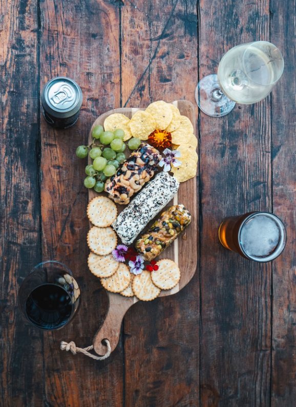Cheese board with crackers, grapes and drinks on a rustic table
