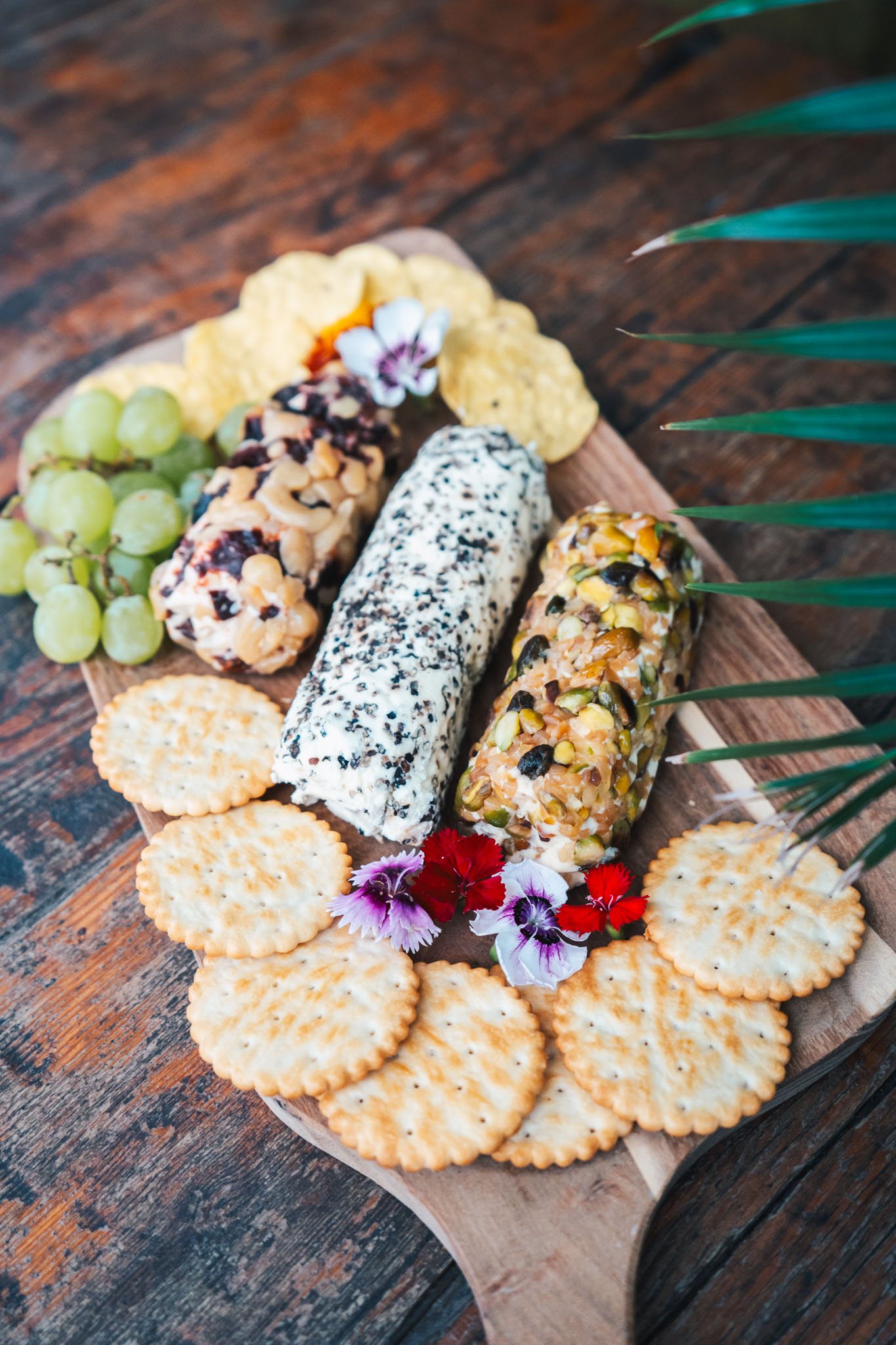 Rolled cheese logs coated in pistachio, cranberry and pepper on a wooden board