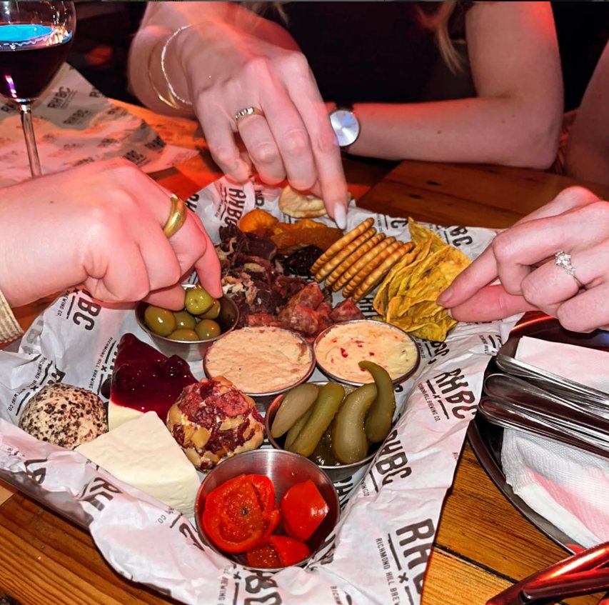Friends sharing a Crafted Dairy platter at a brewery